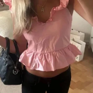Rosa hm volangtopp med öppen rygg - Supersöt rosa topp med volanger. PRISLAPP KVAR!!! Aldrig använd. Bilder lånad! Skriv för egna. Storlek M! Inte lika kort som på annons bilden för att den är i storlek xs och den jag säljer är i storlek M🩷🩷pris kan diskuteras vid snabb affär 