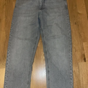 Gråa relaxed jeans från Jack & Jones - Snygga grå jeans från Jack & Jones i modellen Relaxed/Chris. De har en avslappnad passform med raka ben och klassisk femficksdesign. Jeansen är tillverkade i mjukt denimtyg och passar perfekt för en chill och stilren look.