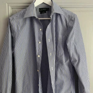  Ralph Lauren skjorta - Snygg blå och vit randig skjorta från Ralph Lauren. Skjortan är i 100% bomull och i nyskick. Skjortan passar M-L