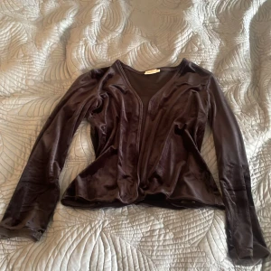 Svart sammetskofta från Part Two - Svart  sammetskofta från Part Two i storlek L. Koftan har lång ärm, v-ringning och en mjuk, glansig yta som ger en lyxig känsla. Perfekt för dig som gillar en elegant och chill stil. Snygg att styla med både jeans och kjol.