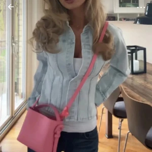 Ljusblå croppad jeansjacka - Säljer en ljusblå jeansjacka med figurnära passform och croppad längd. Jackan har klassisk krage, långa ärmar och knappar framtill. Snygga sömdetaljer ger en modern vibe. Perfekt att slänga över en topp till jeans eller kjol. Helt slutsåld, från hm!