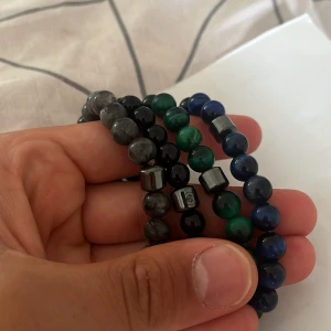 Pärlarmband  - Tre elastiska armband med runda pärlor i svart, grått, grönt och blått. Några pärlor är metalliska och kubformade, vilket ger en cool kontrast. Perfekta för att ge din stil en unik touch och funkar lika bra tillsammans som var för sig. Svarta är från allcap1 resten vasti!