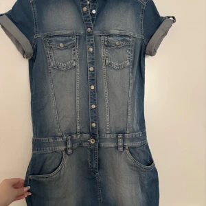 Jeansklänning från Denim by Lindex - Snygg jeansklänning i klassisk blå denim köpt för många år sedan från Lindex. Kortärmad modell med knappar hela vägen framtill, två bröstfickor och stora fickor vid höfterna. Perfekt för dig som gillar en avslappnad men cool stil.