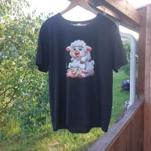 Svart t-shirt med fårtryck - Svart t-shirt med ett stort, färgglatt tryck av två tecknade får på framsidan.står xxl men är som L Klassisk rund hals och korta ärmar. Skön och avslappnad passform, perfekt för dig som gillar roliga motiv och vill sticka ut lite extra.