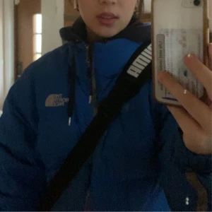The North Face - Säljer en blå dunjacka från The North Face. Den är lite sliten på armen men det är inget man märker av. Säljer den för att den inte kommer till användning längre.