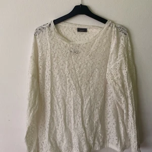 Vit spetsblus från Yessica C&A - Superfin vit blus med inbyggt linne från Yessica med lång ärm och vackert blommigt spetsmönster. Blusen har rund halsringning och är helspetsad vilket ger en romantisk och luftig känsla. Perfekt att styla med jeans eller kjol för en fräsch look.