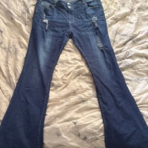 Jeans  - Säljer ett par blå bootcut jeans med snygga slitningar fram. Använd få antal gånger. Vet tyvärr inte vart den är ifrån eftersom det står inte på jeansen 
