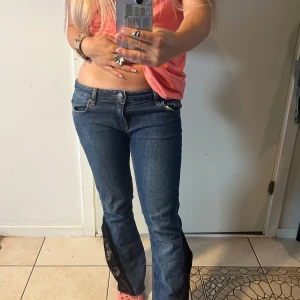 Blå lågmidjade jeans  - Unika blå jeans med låg midja och raka ben, där bensluten har coola svarta spetsinsatser och råa kanter. Dessa är självsydda med symaskin. Jag har en dubblett av jeansen som har hållt i snart 3 år. Dessa har jag däremot inte använt. Stl: 27, 34! ⚡️Fråga om du har några som helst undringar! 🥰
