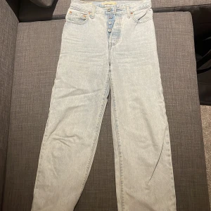 Levi's Ribcage Straight Ankle jeans ljusblå - Ljusblå Levi's Ribcage Straight Ankle jeans med hög midja och raka ben. Klassisk femficksmodell med knappgylf och snygga kontrastsömmar. Perfekt för dig som gillar en retro vibe och vill ha ett par riktigt schyssta jeans i 100% bomull.