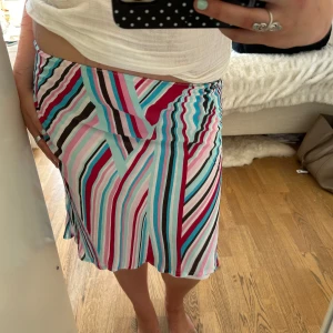 2000s Y2K striped Carrie Bradshaw style silky maxiskirt   - Säljer en midjelång kjol med färgstarka ränder i rosa, turkos, vinröd, svart och vitt. Kjolen har en rak passform och är tillverkad i ett lätt, flowy material som känns perfekt för varmare dagar. Snygg att styla med en enkel topp. 