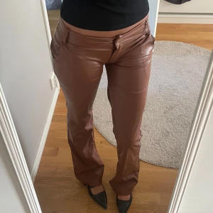 Bruna skinnbyxor bootcut  - Snygga bruna byxor i skinnimitation med bootcut-snitt och låg midja. Byxorna är as snygga till fest! 