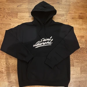 Saint Laurent hoodie - Riktigt fet och eftertraktad hoodie med saint laurent loggan. Storlek M, skick 10/10!! Är lite osäker på äktheten så därför är priset just nu på 1299kr! Nypris runt 7000! Ser precis ut som originalet! Tveka inte med att ställa frågor!