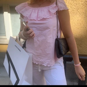 Ralph lauren offshoulder topp - Supersöt ljusrosa blus med offshoulder från Ralph lauren.  Blusen har broderade hål och vågig kant både upptill och nertill. Perfekt för en somrig look och passar till både jeans och kjol.