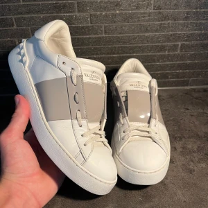 Valentino Garavani Open sneakers vit/grå - Snygga Valentino Garavani Open sneakers i vitt skinn. Storlek 38, extremt fint skick 9/10 enbart använda ett fåtal gånger. Hör av er vid frågor 