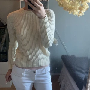 Ribbstickad vit tröja från H&M - Säljer en ribbstickad vit tröja från H&M i storlek S. Tröjan har lång ärm, rund halsringning och är gjord i ett mjukt stickat material. Perfekt för lager-på-lager och enkel att matcha med olika outfits.