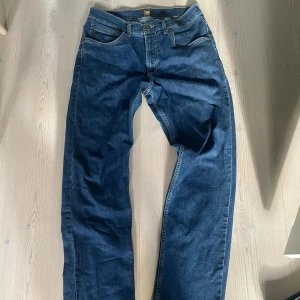 Mörkblå Lee Brooklyn jeans W30 L32 - Snygga mörkblå jeans från Lee, modell Brooklyn. Klassisk femficksdesign med raka ben och normal passform. Jeansen är tillverkade i slitstarkt denimtyg och har kontrastsömmar. Perfekta för dig som gillar en tidlös look. 