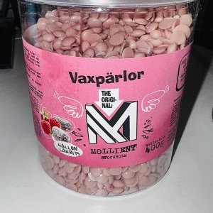 Vaxpärlor Hallon Lakrits 400g Mollient - Vaxpärlor i ljusrosa färg med doft av hallon och lakrits från Mollient. Perfekta för remsfri vaxning och enkel att smälta till en jämn konsistens. Kommer i en stor burk på 400g med tydliga instruktioner på förpackningen.
