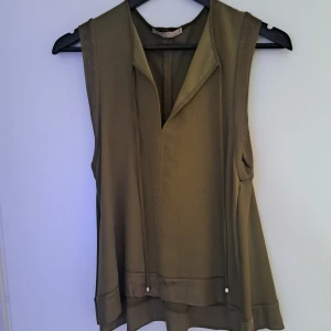Olivgrön top från Zara - Snygg olivgrön top från Zara med v-ringad hals och breda axelband. Det har en lös passform och är tillverkad i ett mjukt, lätt material. 100% nytt.