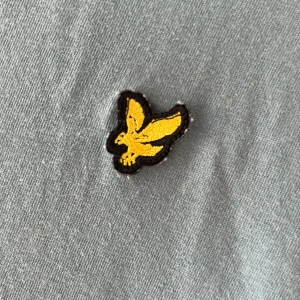 Blå t-shirt från Lyle & Scott - Snygg blå t-shirt från Lyle & Scott med klassisk gul fågel-logga på bröstet. Enkel och stilren design med rund hals och korta ärmar. Perfekt för dig som gillar en clean look och vill ha något bekvämt i garderoben.