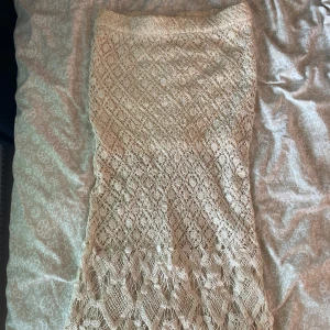 Beige virkad midikjol  - Superfin, beige virkad midikjol med vågig nederkant. Kjolen har ett detaljerat mönster och känns riktigt bohemisk och somrig. Perfekt för dig som gillar unika plagg med mycket struktur och snygga detaljer.