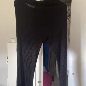 Svarta ribbade mjukisbyxor - Svarta mjukisbyxor med ribbad struktur och resår i midjan. Byxorna har raka ben och är tillverkade i ett mjukt, stretchigt material som känns skönt mot huden. Perfekta för chill dagar hemma eller när du vill ha en avslappnad look.