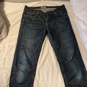 Mörkblå jeans från WESC, modell Eddy - Snygga mörkblå jeans från WESC, modell Eddy. Klassisk femficksdesign med kontrastsömmar och coolt broderi på bakfickorna. Jeansen har en gul patch bak i midjan och är tillverkade i slitstarkt denimtyg. Perfekta för en avslappnad streetstil.