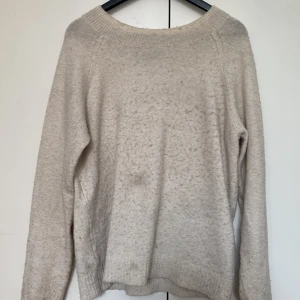 Beige stickad tröja från Vero Moda - Mysig beige stickad tröja från Vero Moda i storlek XS. Tröjan har en bred ribbad halsringning och långa ärmar. Perfekt för lager-på-lager och chill höst- och vinterdagar. Enkel och stilren design som passar till det mesta.