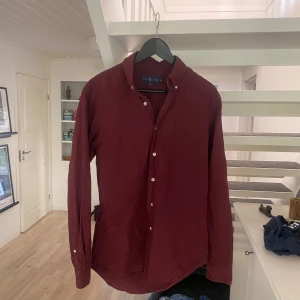 Vinröd skjorta från Ralph Lauren - Snygg vinröd skjorta från Ralph Lauren i slim fit-modell. Sitter perfekt och är en jätte najs färg för vintern som kommer. Ny pris är 1500 så mitt pris är en steal för hur lite den användts.
