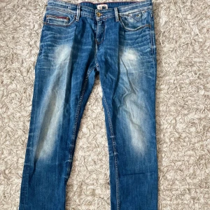 Hilfiger Denim blå jeans 34/34 - Snygga blå jeans från Hilfiger Denim med klassisk femficksdesign och slitna detaljer på både fram- och baksida. Jeansen har normal passform, raka ben och är tillverkade i robust bomullsdenim. Perfekt för dig som gillar en avslappnad och cool stil.