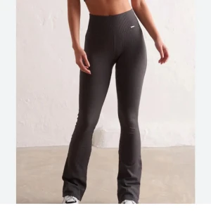 Ribbade gråa bootcut leggings - Snygga gråa ribbade leggings med bootcut och hög midja. Stretchigt material som sitter tajt upptill och släpper ut vid benslutet. 