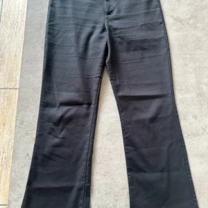 Svarta bootcut byxor från Zara - Svarta bootcut byxor från Zara i klassisk modell med hög midja. Byxorna har en stilren look och är tillverkade i ett mjukt material som känns bekvämt hela dagen. Perfekta att styla med sneakers eller boots för en trendig vibe.