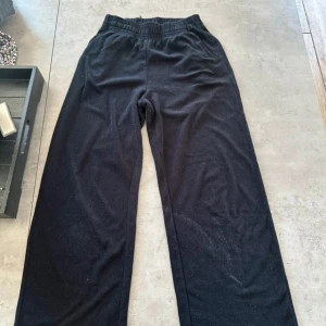 Svarta mjukisbyxor från H&M XS - Svarta mjukisbyxor från H&M i storlek XS. Byxorna har resår i midjan och är tillverkade i mjukt material som känns skönt mot huden. De har en rak och loose passform, perfekta för chill dagar eller när du vill vara bekväm.