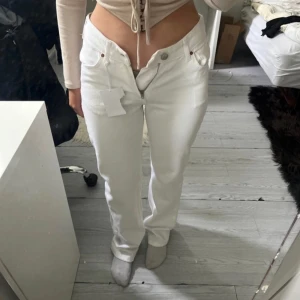 Vita straight jeans från Never Denim - Säljer ett par vita jeans från Never Denim, modell JP Low Straight. Byxorna har låg midja, raka ben.