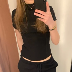 Svart polotopp från Zara - Säljer en svart polotopp från Zara med korta ärmar och figurnära passform. Finns dragkedja i bak och på sidan. Materialet är inte stretchigt. Knappt använt.