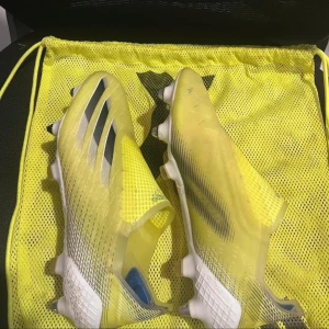 Gula adidas fotbollsskor utan snörning - Säljer ett par riktigt snabba gula adidas fotbollsskor med svarta detaljer och vita sulor med metall- och plastdobbar. Skorna har en strömlinjeformad design utan snörning och är tillverkade i syntetmaterial för bästa passform och känsla på planen. Make sure you realise these are a uk 7.5 so it’s a 41 or 42 euro