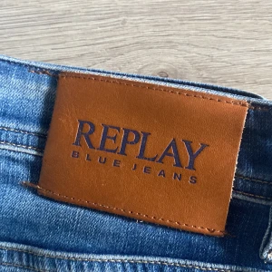 Replay Grover blå jeans straight fit - Säljer ett par Replay Grover jeans i klassisk blå tvätt med straight fit. Jeansen har fem fickor, snygga kontrastsömmar och en brun läderpatch med Replay-logga bak. Materialet är slitstarkt denim och passformen är normal med raka ben.
