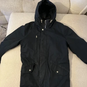 Marinblå jacka från Elvine, M - Marinblå jacka från Elvine med luva. Jackan har hel dragkedja framtill och snygga detaljer i metall. Perfekt snygg jacka till sen höst/vinter 