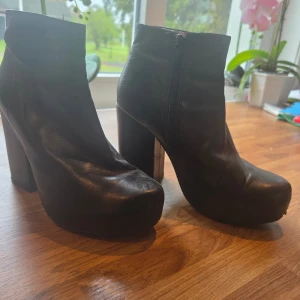 Svarta Vagabond stövletter, svart, stl 38 - Svarta stövletter från Vagabond med hög klack och platåsula. Skorna har rund tå, dragkedja på sidan och stilren design som ger en edgy vibe. Perfekta för dig som gillar statement boots med attityd.