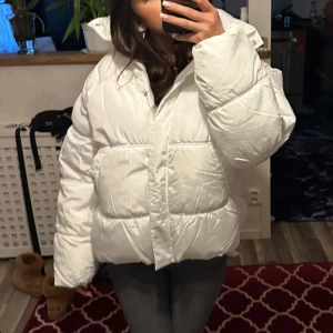 Vit pufferjacka - Säljer en riktigt fluffig och varm vit pufferjacka med hög krage och stora fickor. Jackan har en oversized passform och stängs med dragkedja. Perfekt för kalla dagar när du vill vara både bekväm och snygg.