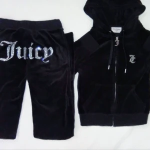 Svart Juicy Couture Set i Nyskick - Fint set från juicy couture i strl xxs, köpt för en månad sen och använt en gång. Hoodien är i mjuk velour och har texten "Juicy" på ryggen, ett stort J på dragkedjan, samt jc logga i strass fram. Byxorna som är i glansig velour har snörning i midjan och den ikoniska jc loggan i strass fram, samt texten Juicy i stora stenar på baksidan.