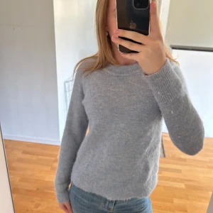 Ljusblå stickad tröja i ullmix - Supermjuk ljusblå stickad tröja med rund hals och långa ärmar. Tröjan har en enkel och clean look med ribbade muddar vid ärmslut och nederkant. Perfekt att slänga på sig när det är kyligt ute.