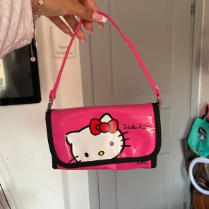 Rosa Hello Kitty axelväska - Söt rosa axelväska från Hello Kitty x Nintendo DS. Den är ganska liten så funkar bättre som än plånbok eller clutch väska💕 Den är helt oanvänd och är längden av en mobil ungefär. Skriv gärna vid frågor🩷 