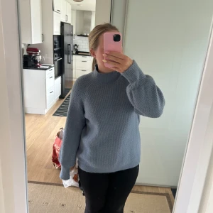 Ljusblå stickad tröja - Supermysig ljusblå stickad tröja med ballongärmar och högre ribbad hals. Tröjan har en loose fit och är perfekt för lager-på-lager. Enkel och stilren design som passar till allt. 