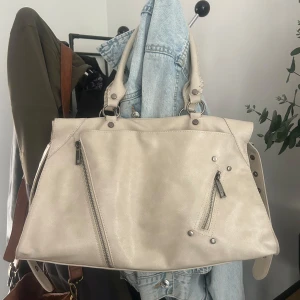 Beige handväska med dragkedjor - Helt ny väska som jag köpte i Spanien. Den är stor och har många fack och är rymlig.