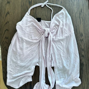 Ljusrosa gina topp - Supersöt ljusrosa halterneck topp med omlott och knyt framtill. Tunn och luftig, perfekt för varma dagar. Snygg att styla med jeans eller kjol för en trendig look.