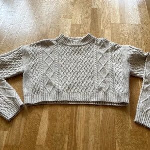Ljus stickad & croppad tröja  - Superfin ljus croppad & stickad tröja från H&M med typ flätmönster. Säljer då den blivit för liten. Den är lite noppig men det syns inte så tydligt. Hör av dig om du har några frågor! 😊
