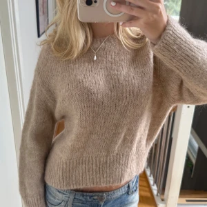 Beige stickad tröja  - Supermysig beige stickad tröja med rund hals och lång ärm. Modellen är lite croppad och har en loose fit som ger en chill vibe. Perfekt att slänga på sig till jeans eller kjol när det är kallare ute. Mjuk och fluffig känsla.