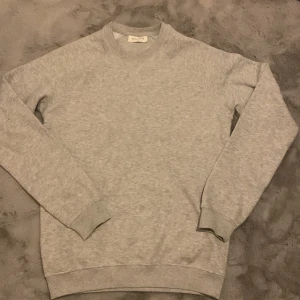 Ljusgrå sweatshirt från Pier One - En stilren ljusgrå sweatshirt från Pier One med klassisk rund halsringning och ribbade muddar. Tröjan är i mjuk bomullsmix och har en relaxed passform, perfekt för chill dagar eller när du vill hålla det enkelt men snyggt.