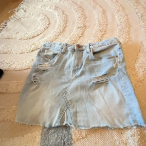 Ljusblå jeanskjol  - Snygg ljusblå jeanskjol  med slitna detaljer och hål 