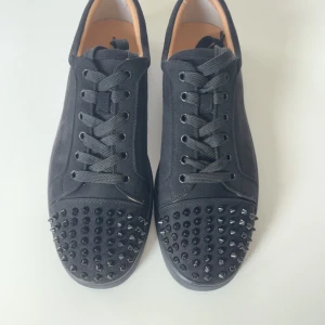 Christian Louboutin svarta sneakers med nitar - Svarta sneakers från Christian Louboutin med klassisk röd sula och coola svarta nitar på tån. Priset går självklart att diskutera o säljer pga att de är för stora, allt finns med box dustbags kvitto kort mm följer såklart med. 